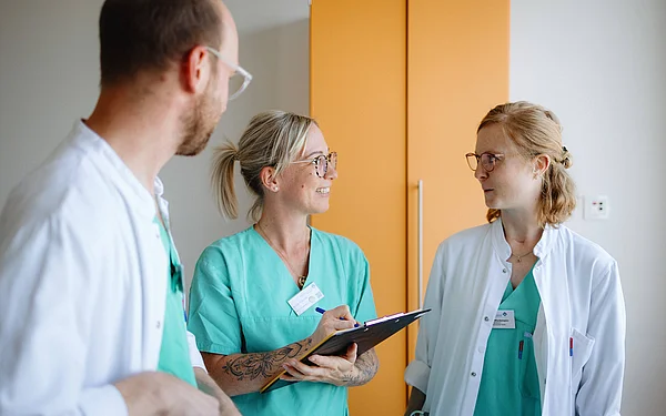 Drei Mitarbeitende aus Medizin und Pflege im gemeinsamen Gespräch.