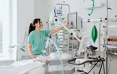 Pflege auf der Intensivstation Pflegekraft versorgt eine Patientin auf einer Intensivstation.
