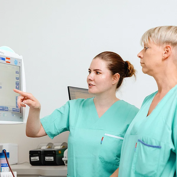 Zwei Pflegekräfte arbeiten gemeinsam, um die Vitalwerte 