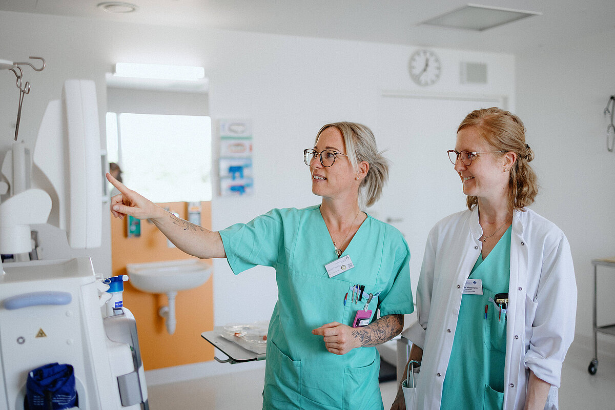 Zwei Mitarbeiterinnen aus Medizin und Pflege arbeiten gemeinsam an einem medizinischen Gerät.