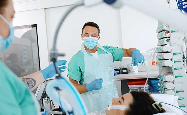Pflegekräfte arbeiten mit einem Beatmungsschlauch am Patientenbett