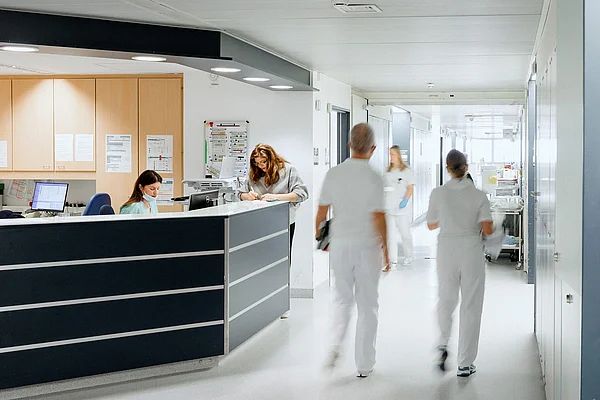 Zwei Pflegekräfte gehen durch einen hellen Krankenhausflur.