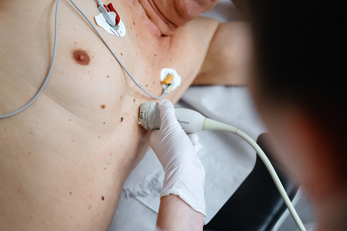 Mitarbeiterin bringt Elektroden am Oberkörper eines Patienten an