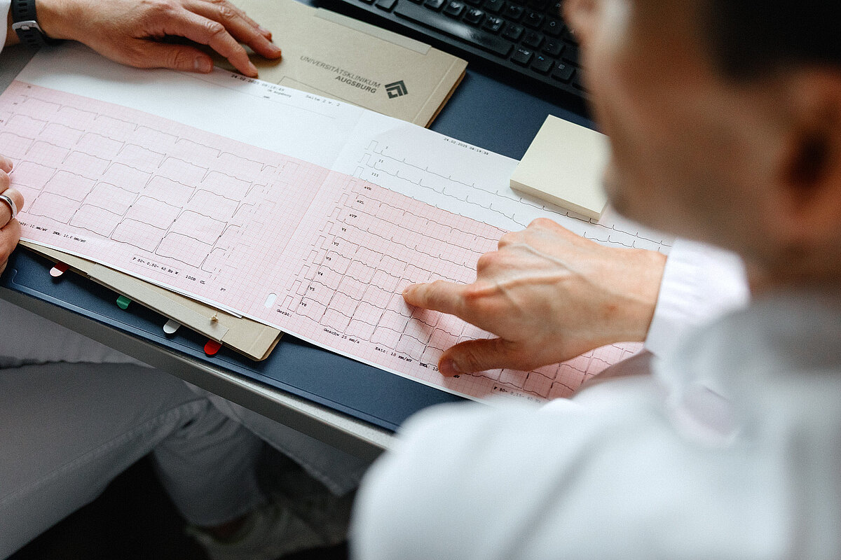 Mitarbeiter wertet einen EKG-Ausdruck aus