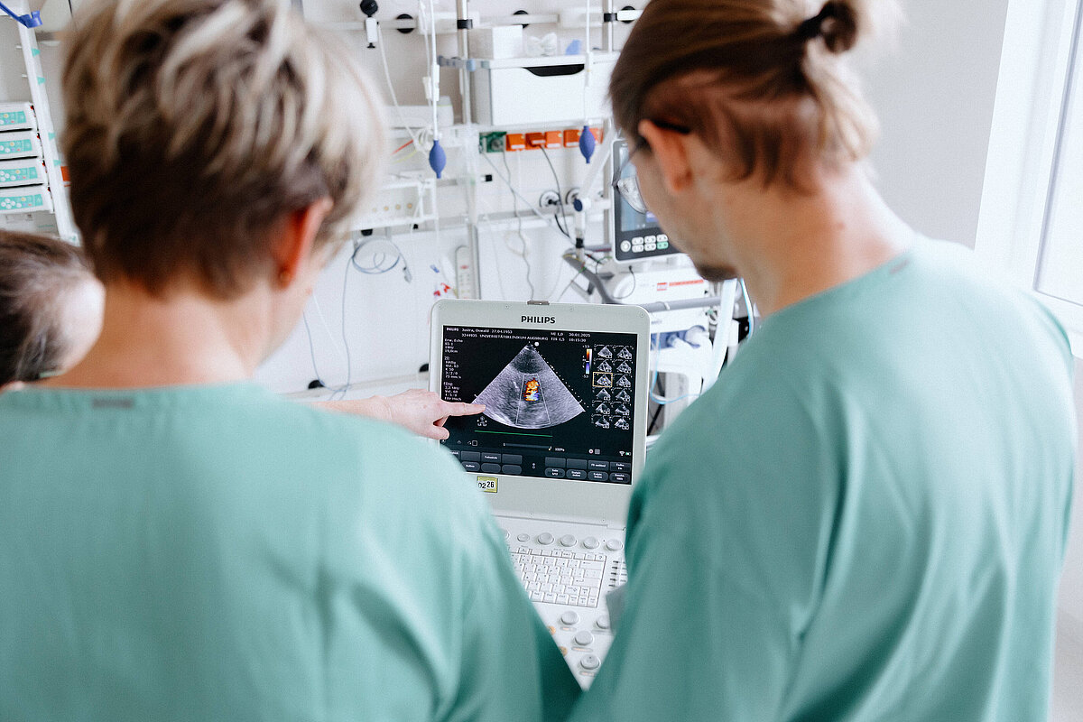 Zwei Pflegekräfte betrachten gemeinsam medizinische Aufnahmen an einem Monitor.