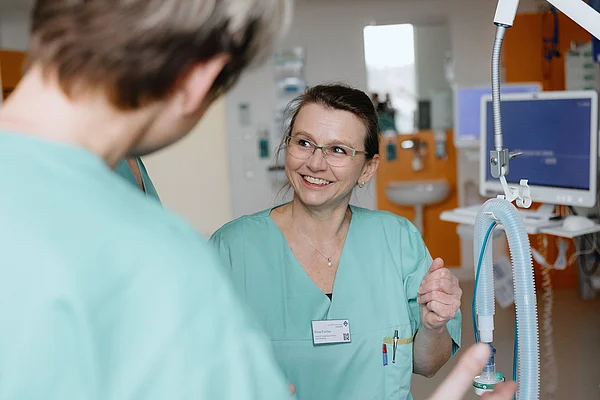 Pflegekraft im Gespräch mit Kollegen im Zentrum für Intensivtherapie