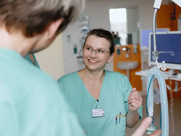 Pflegekraft im Gespräch mit Kollegen im Zentrum für Intensivtherapie