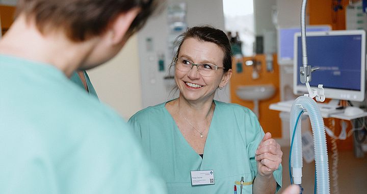 Pflegekraft im Gespräch mit Kollegen im Zentrum für Intensivtherapie