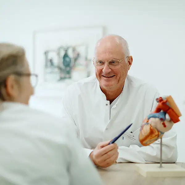 Arzt erklärt mit einem Herzmodell einer Kollegin eine medizinische Thematik in einer Klinik.