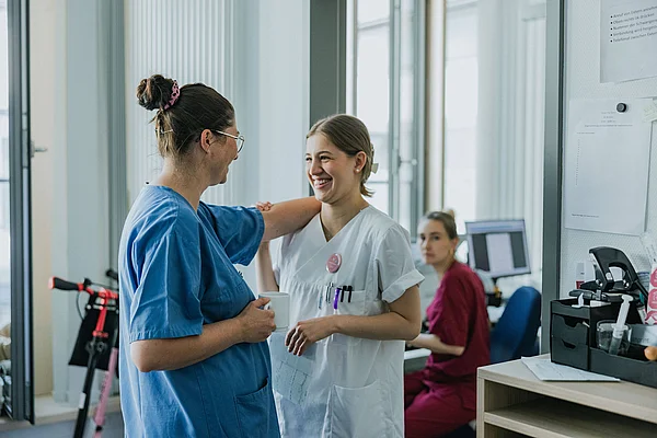 Zwei Mitarbeitende im Gesundheitswesen im Gespräch auf einer Krankenhausstation.