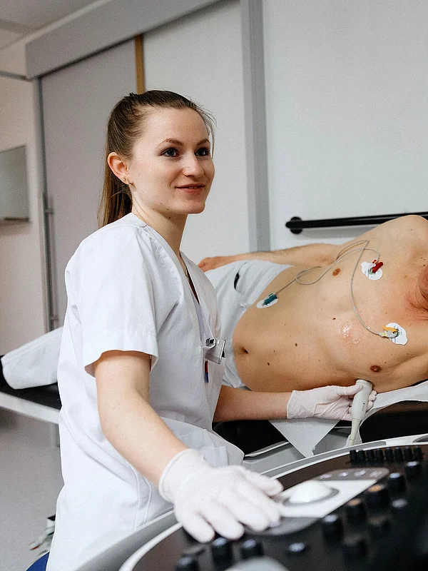 Mitarbeiterin mit medizinischer Simulationspuppe auf einer Liege